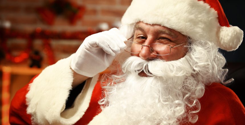 Portrait of happy Santa Claus holding Christmas letter in his hands and looking at camera